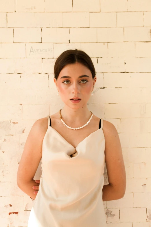 woman wearing an elegant necklace stands near a wall