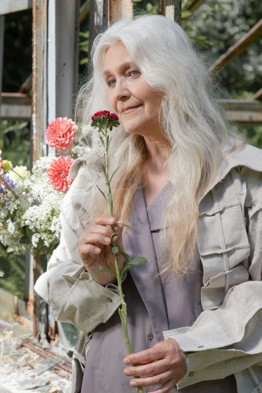 a woman wearing a gray outfit holding flowers