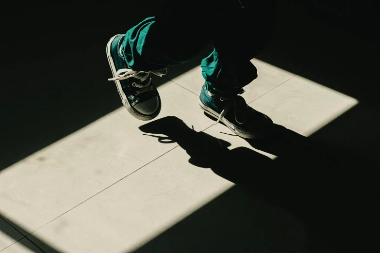 a shadow of a man in green jacket walking on concrete