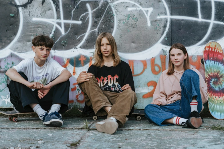 a group of young people sitting in front of a wall with graffiti