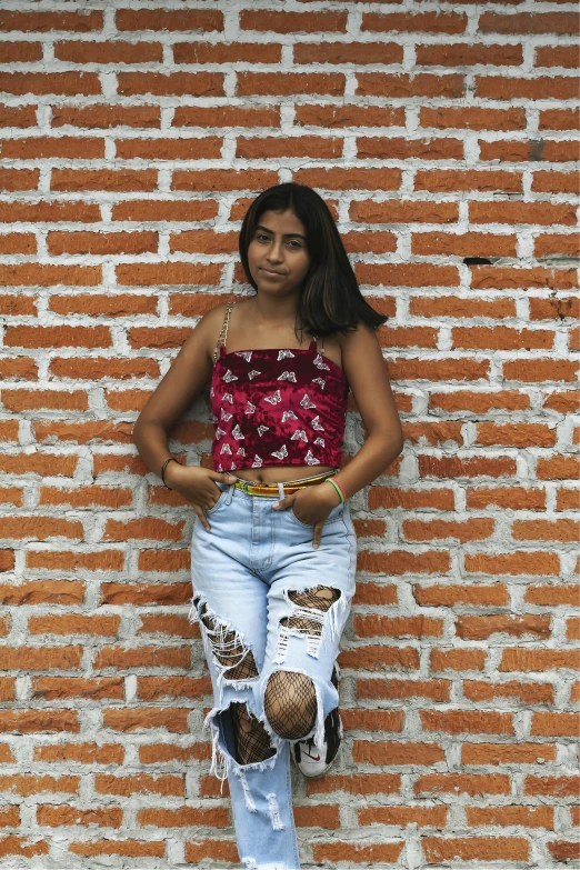 a girl is posing on a brick wall