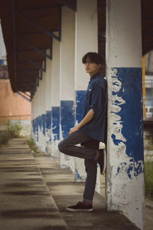 a young man standing against a wall outside of a building