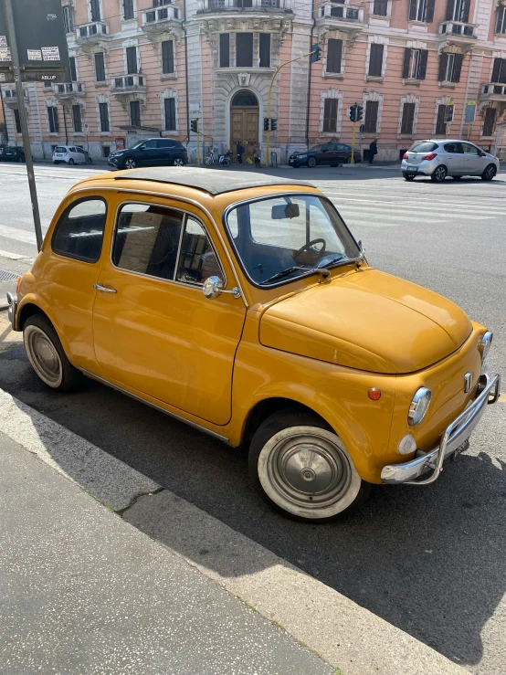 a yellow small car is parked on the side of the street