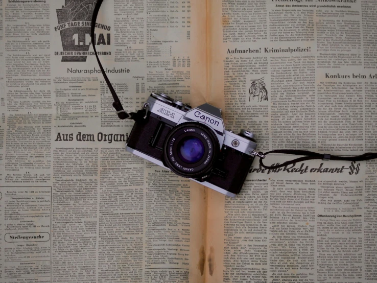 an old camera is hanging from the pages of an old newspaper