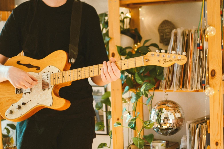 a man holding a yellow guitar and wearing a black shirt