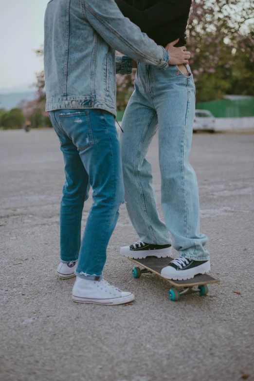 two people on a skate board standing beside one another