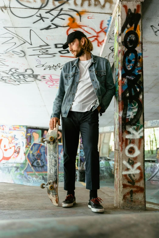 a man standing holding a skate board near graffiti