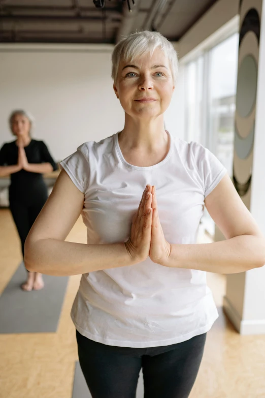 an older woman sitting in yoga mats at a yoga class