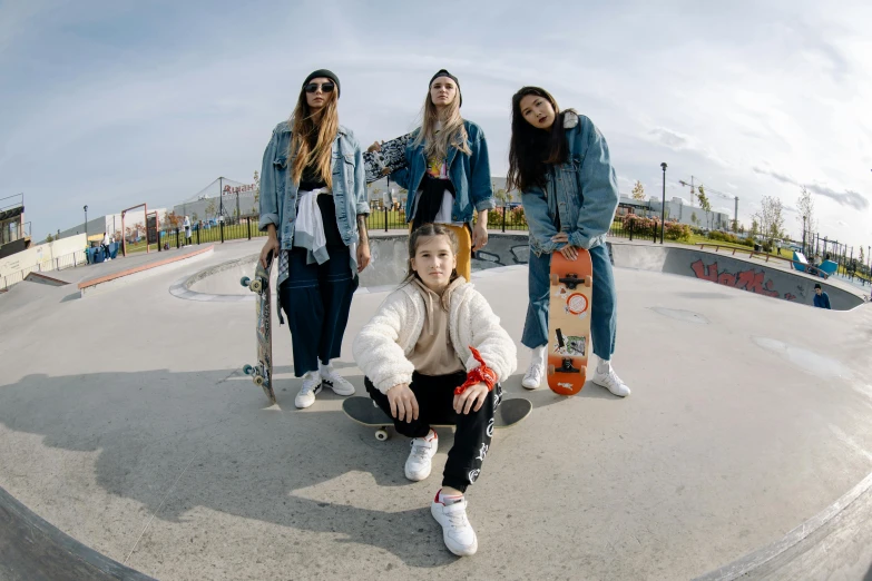 four young ladies sitting on concrete holding their skateboards
