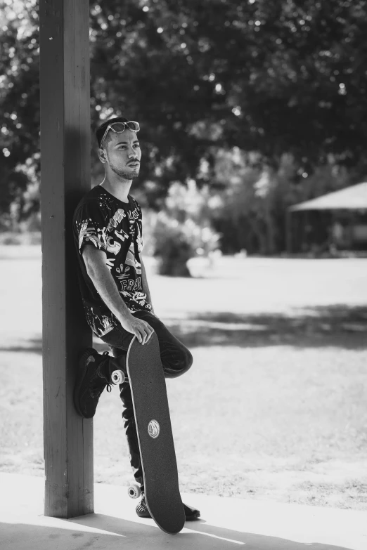 a person is leaning against a pole with their skateboard