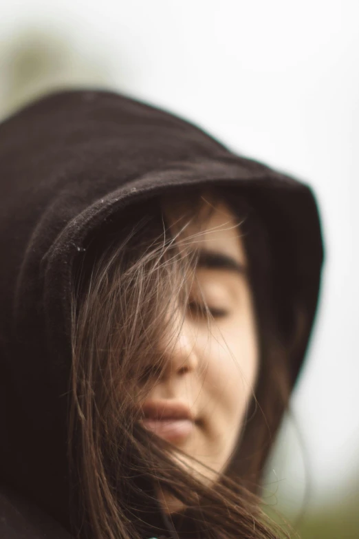 a close - up of a young woman with closed eyes and a black hood