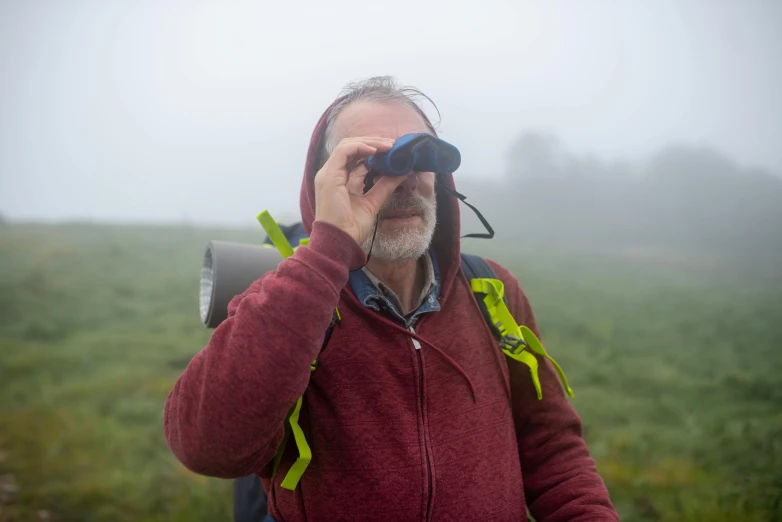 a man looking through binoculars on a cloudy day