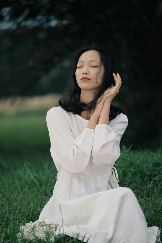 a girl wearing a white shirt and skirt, sitting on a grass field