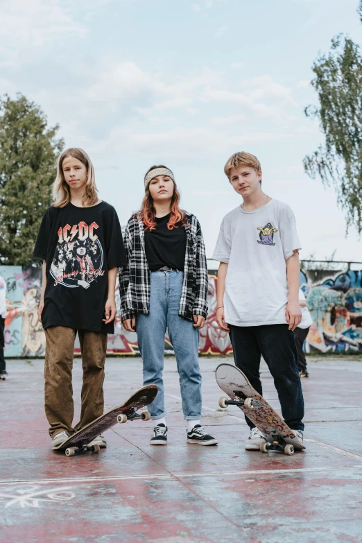 three teenaged boys are posing with their skateboards