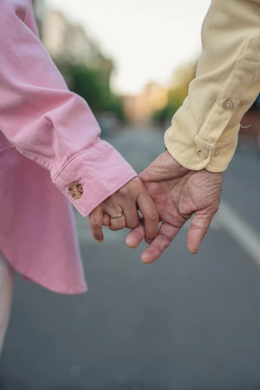 two people hold hands as they walk down the street