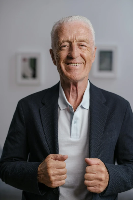 an old man wearing a black suit coat posing for a po