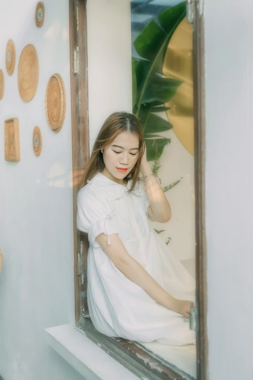 a woman wearing a white dress looks out of a window