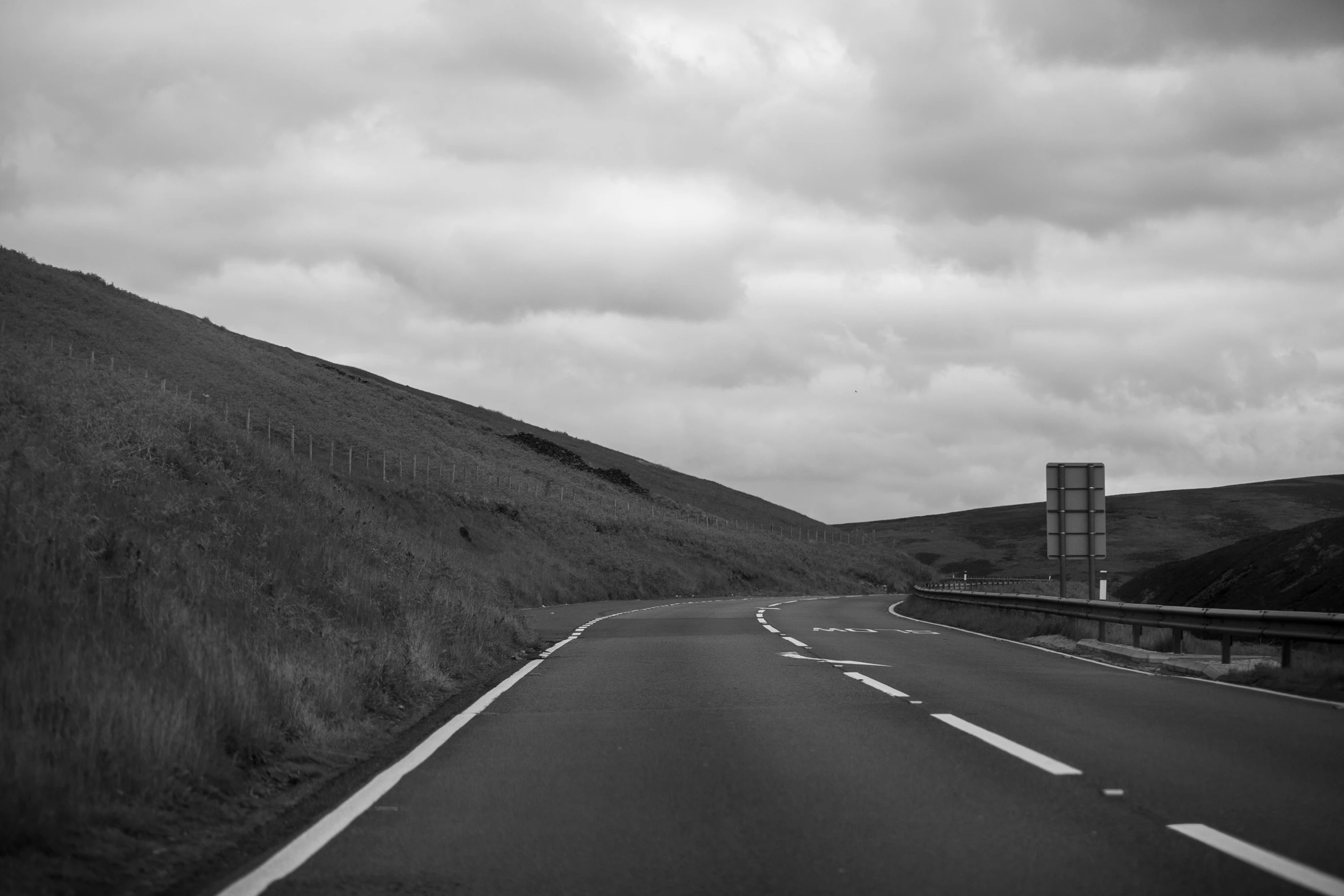 a highway and grassy hill in the rain