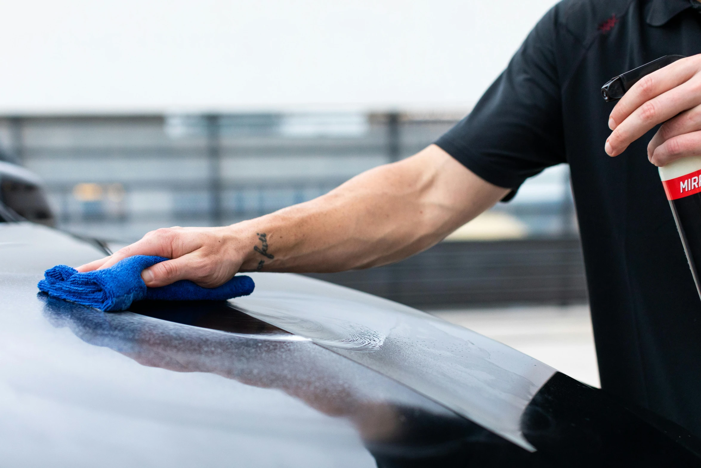 man polishing a car with a blue rag