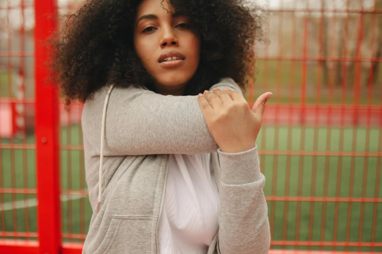 a woman with curly hair is posing in front of a fence