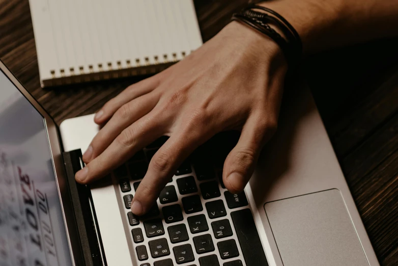 a man typing on a laptop with his hand