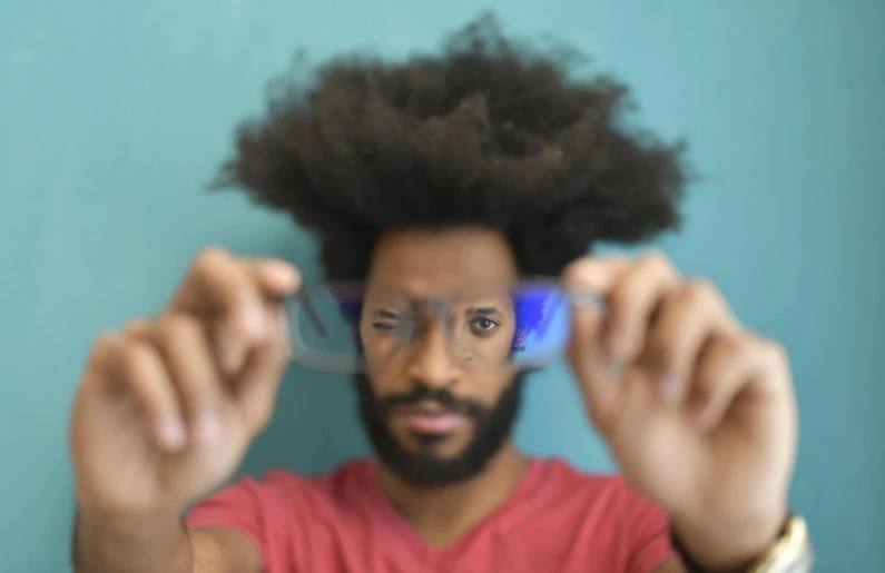 man with afro holding a blue toothbrush while wearing glasses
