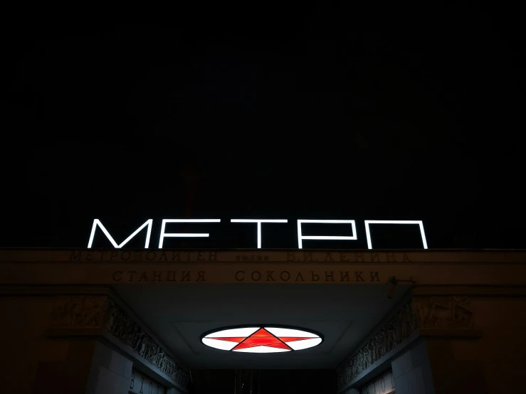 a neon sign for the metro station lit up on the roof