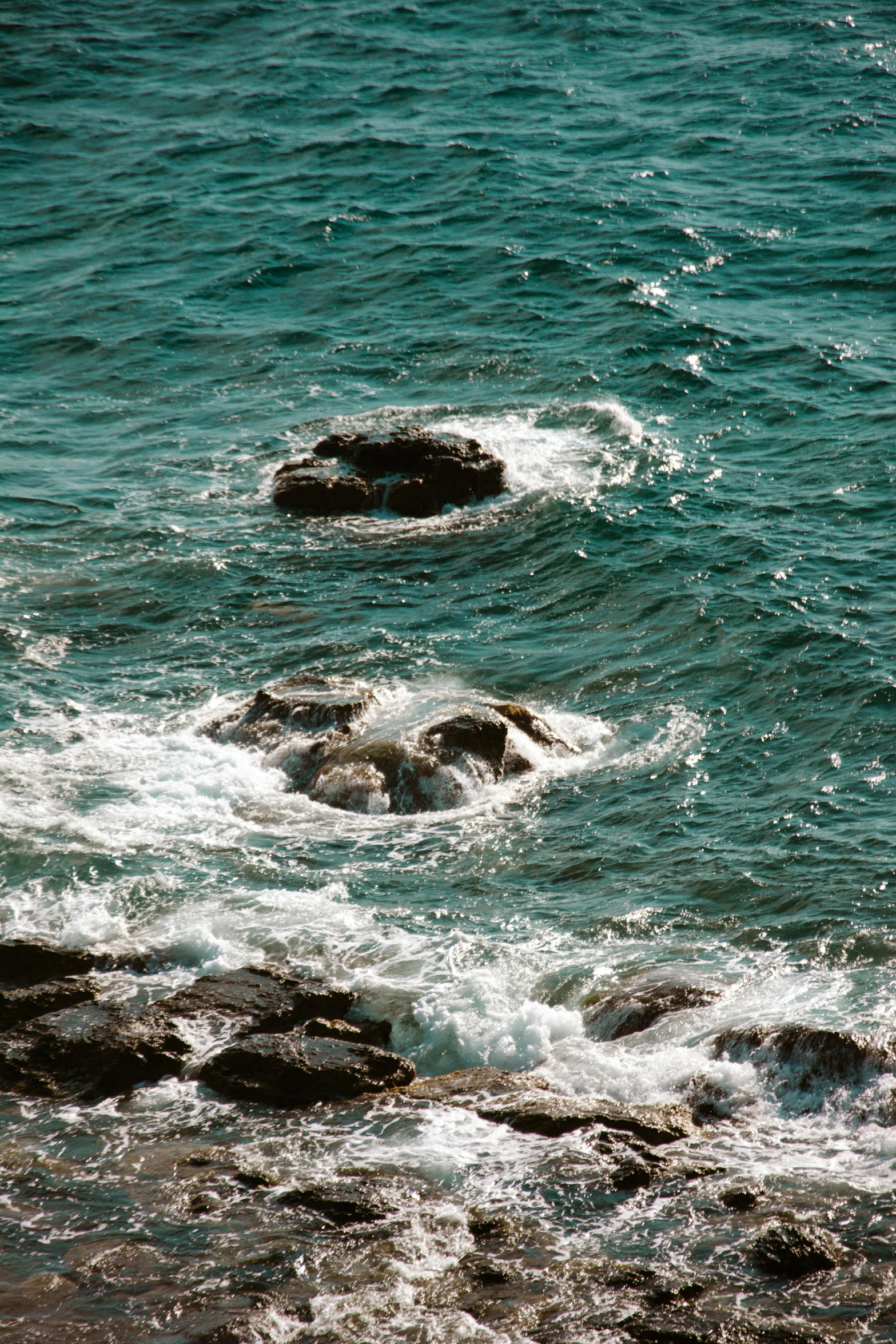 two rocks in the water on a beach