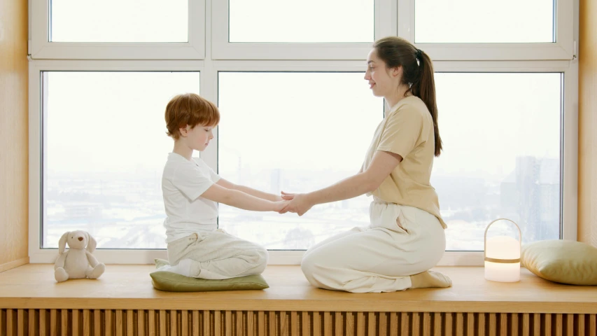 a woman sitting next to a boy who is playing with a toy