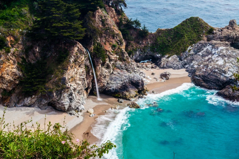 a large waterfall in the side of a cliff near the ocean