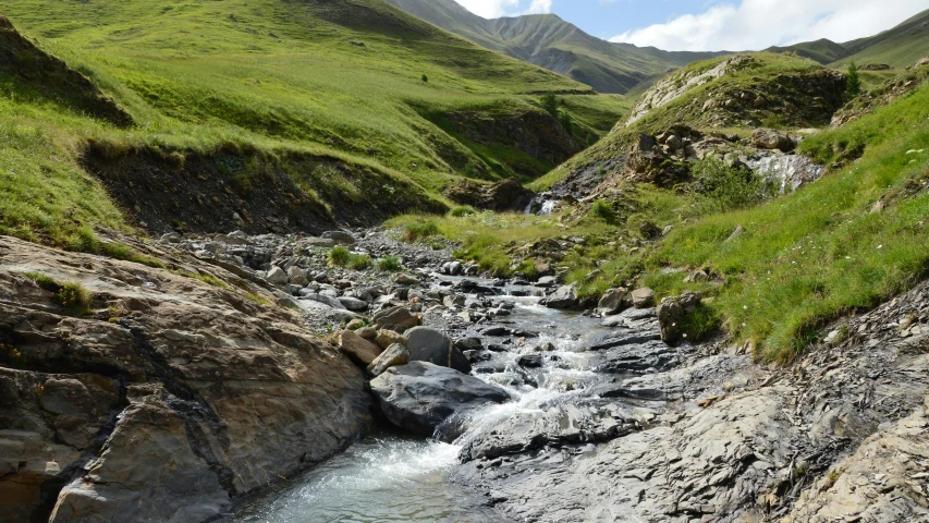 a stream running through a valley in a grassy valley