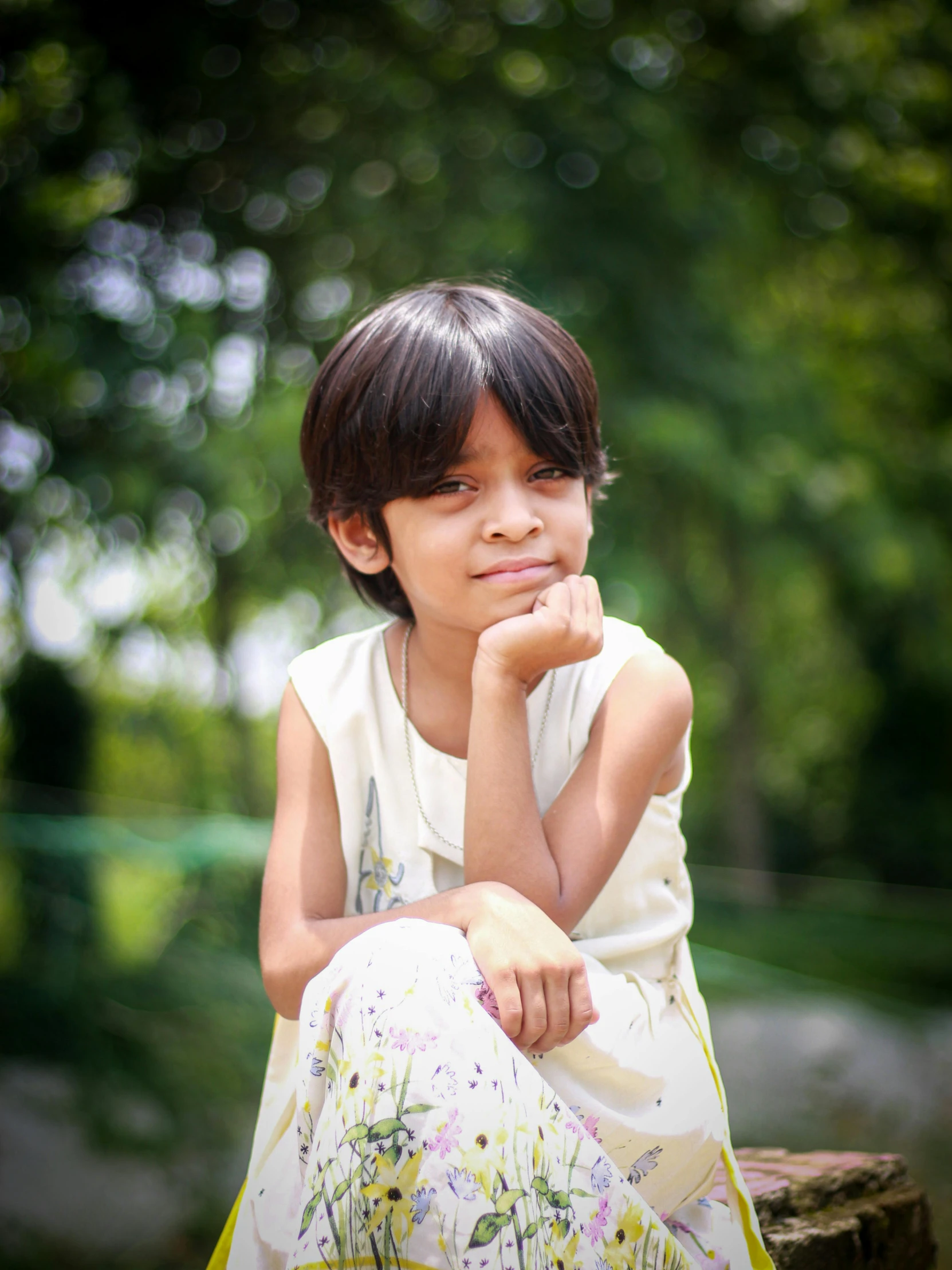 a  sitting on a tree stump with her chin resting on her hand