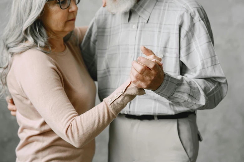 a lady and man are posing together on the grey wall