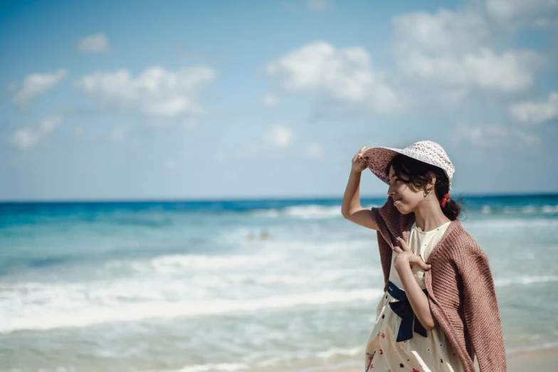 woman in straw hat walking on beach with open ocean