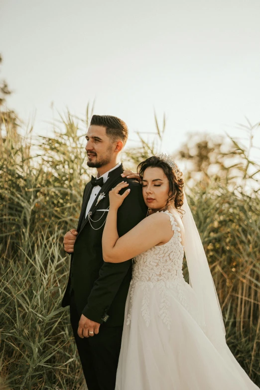 a bride and groom standing near some sand bushes