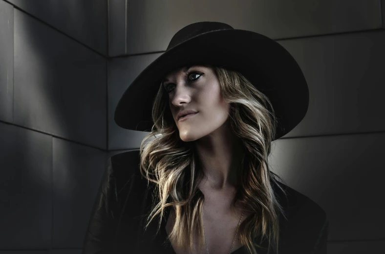 a woman with long hair wearing a black cowboy hat