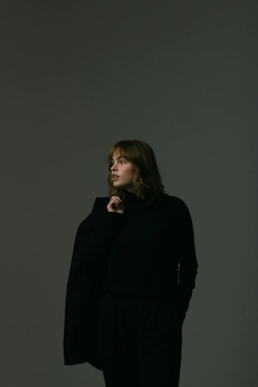 a woman standing against a gray background posing