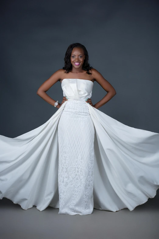 a young woman in a wedding gown standing with her arms around her chest