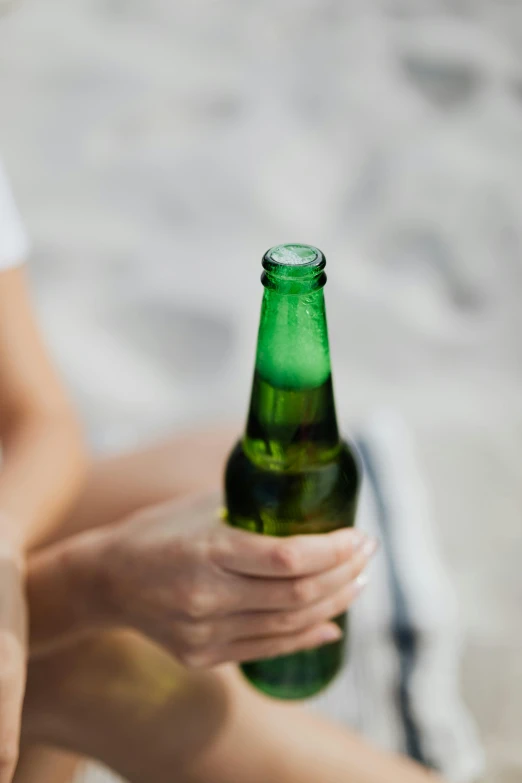 woman with hand on beer bottle sitting in a towel