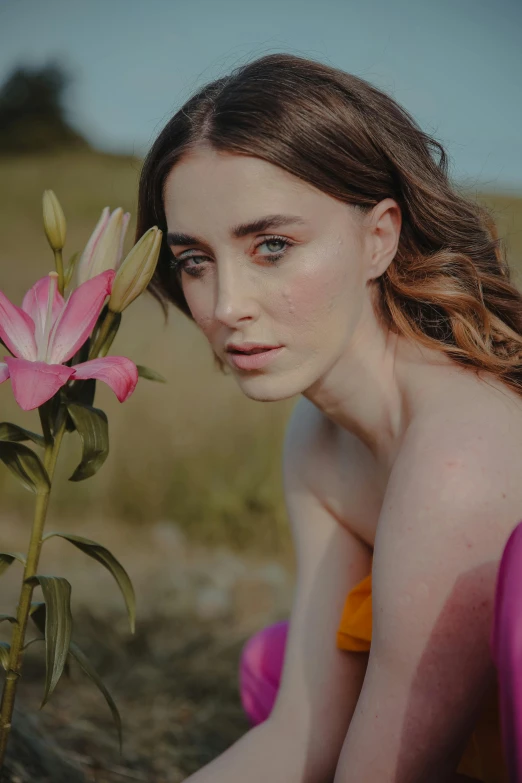 a woman is posing in the field with her flowers