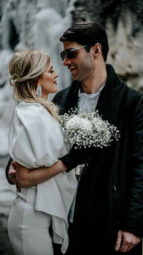 a man and woman looking at each other near a waterfall