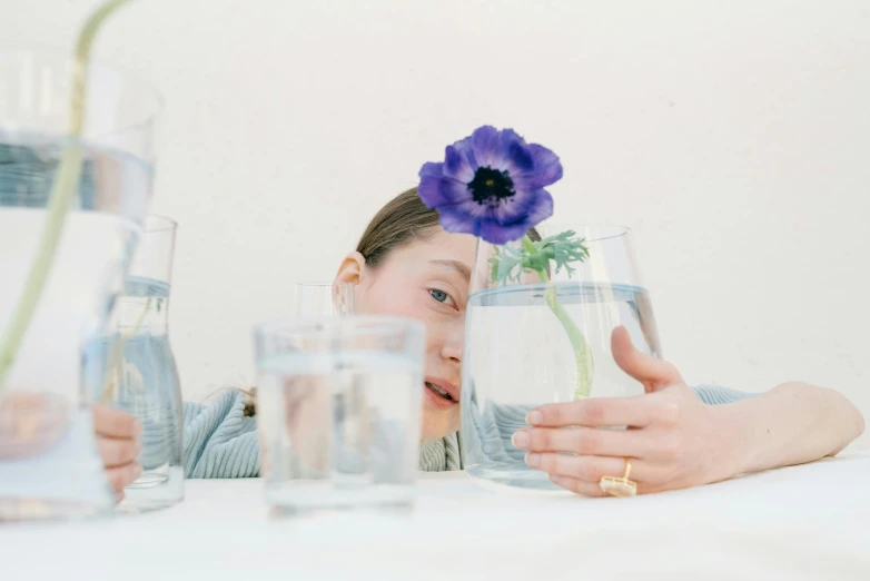 a  holding a glass vase filled with water and an flowers