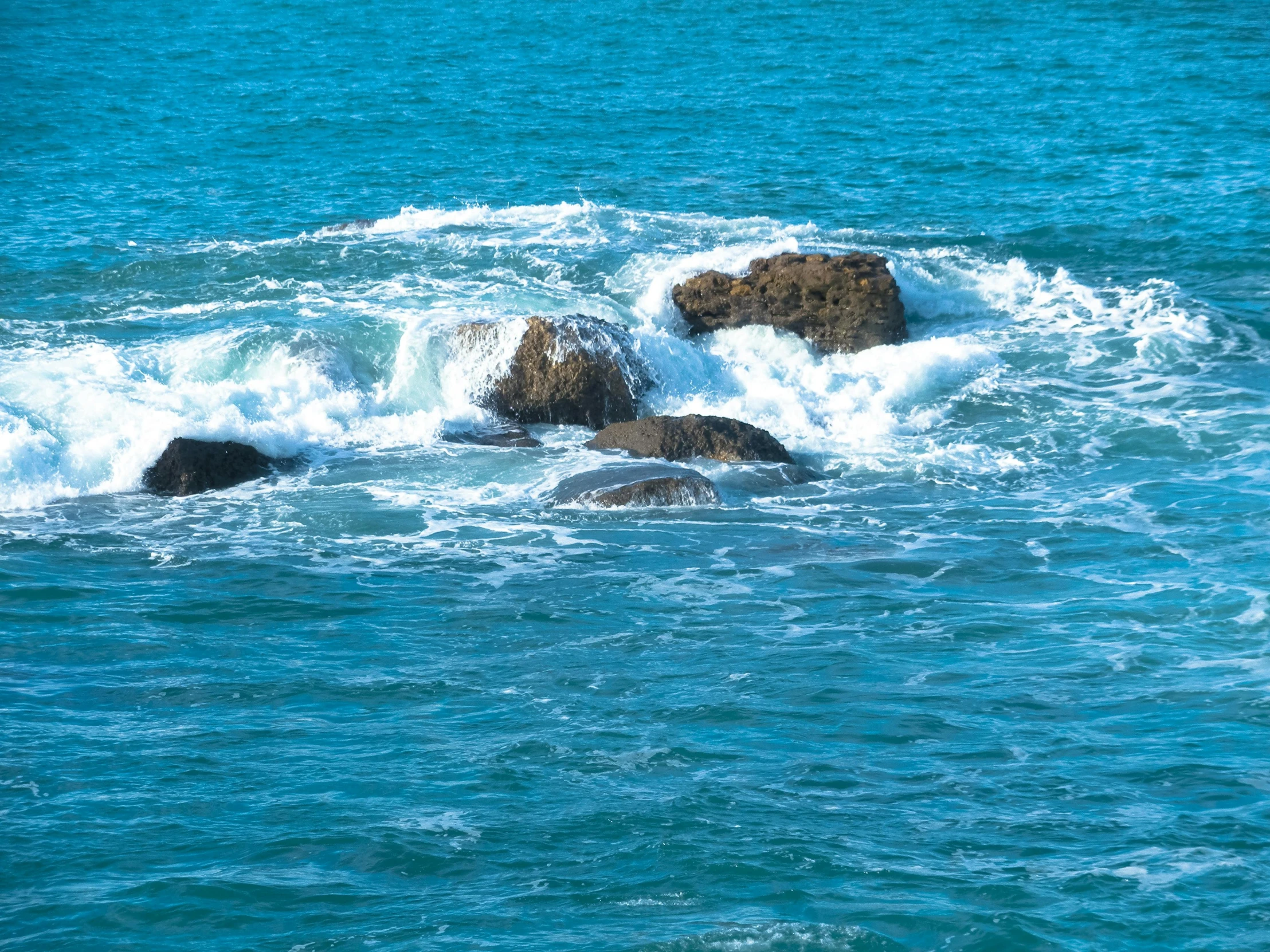 several large rocks are sitting out in the water