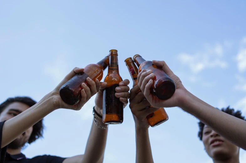 some people holding up their bottles in front of the sky