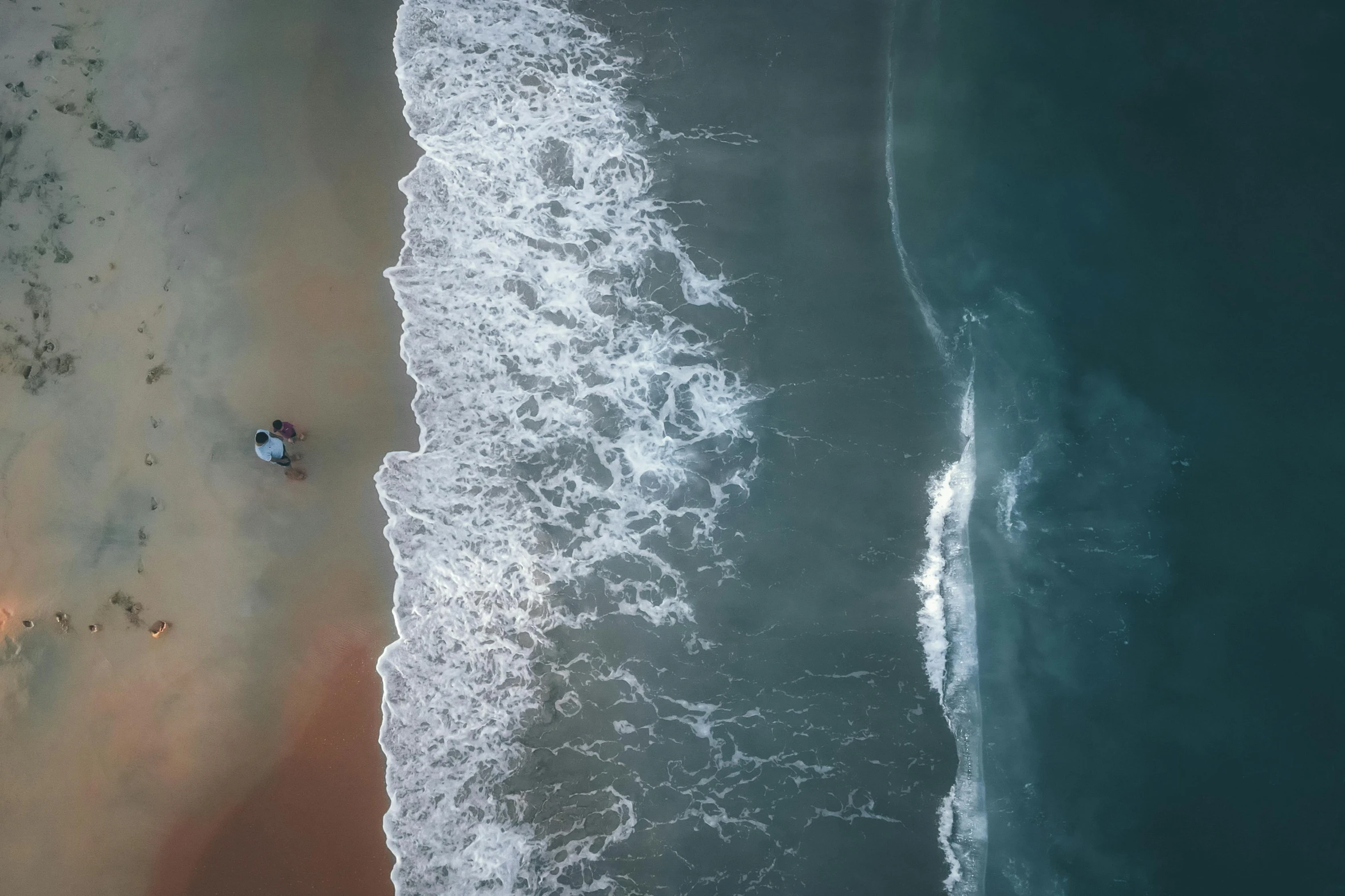 a beach that has two umbrellas at the ocean's edge