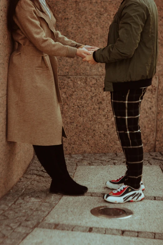 two people in black pants and green jacket holding hands with each other