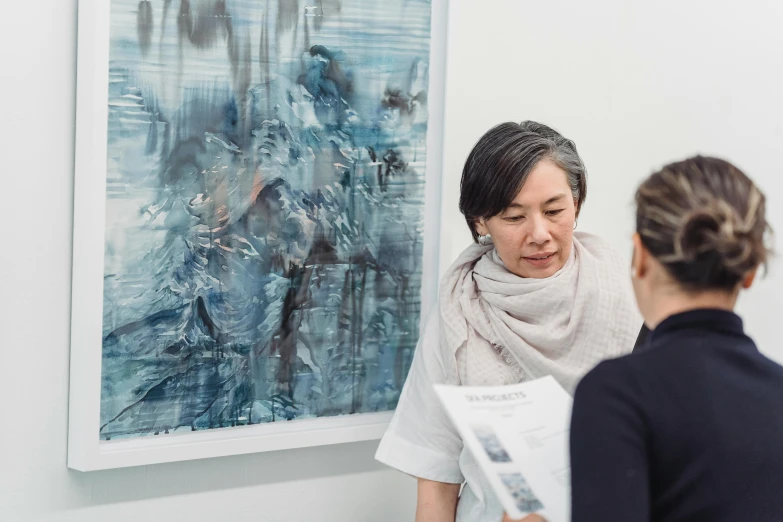 two women sitting by a painting looking at each other