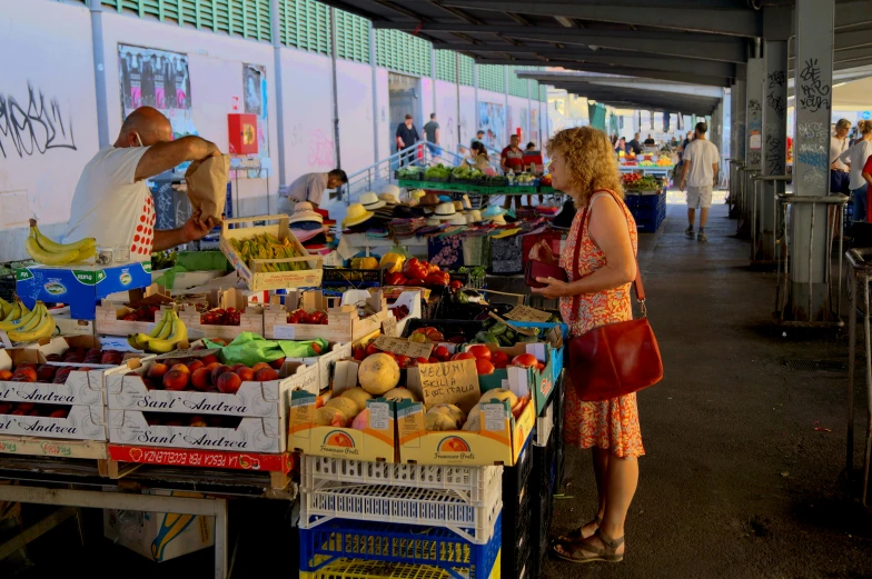 a woman in an orange and white dress shopping at a fruit market