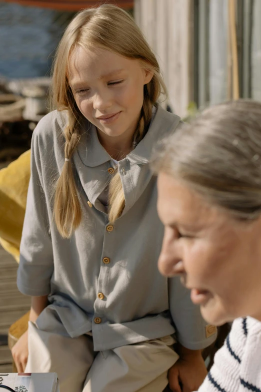 two girls are sitting outside using a laptop