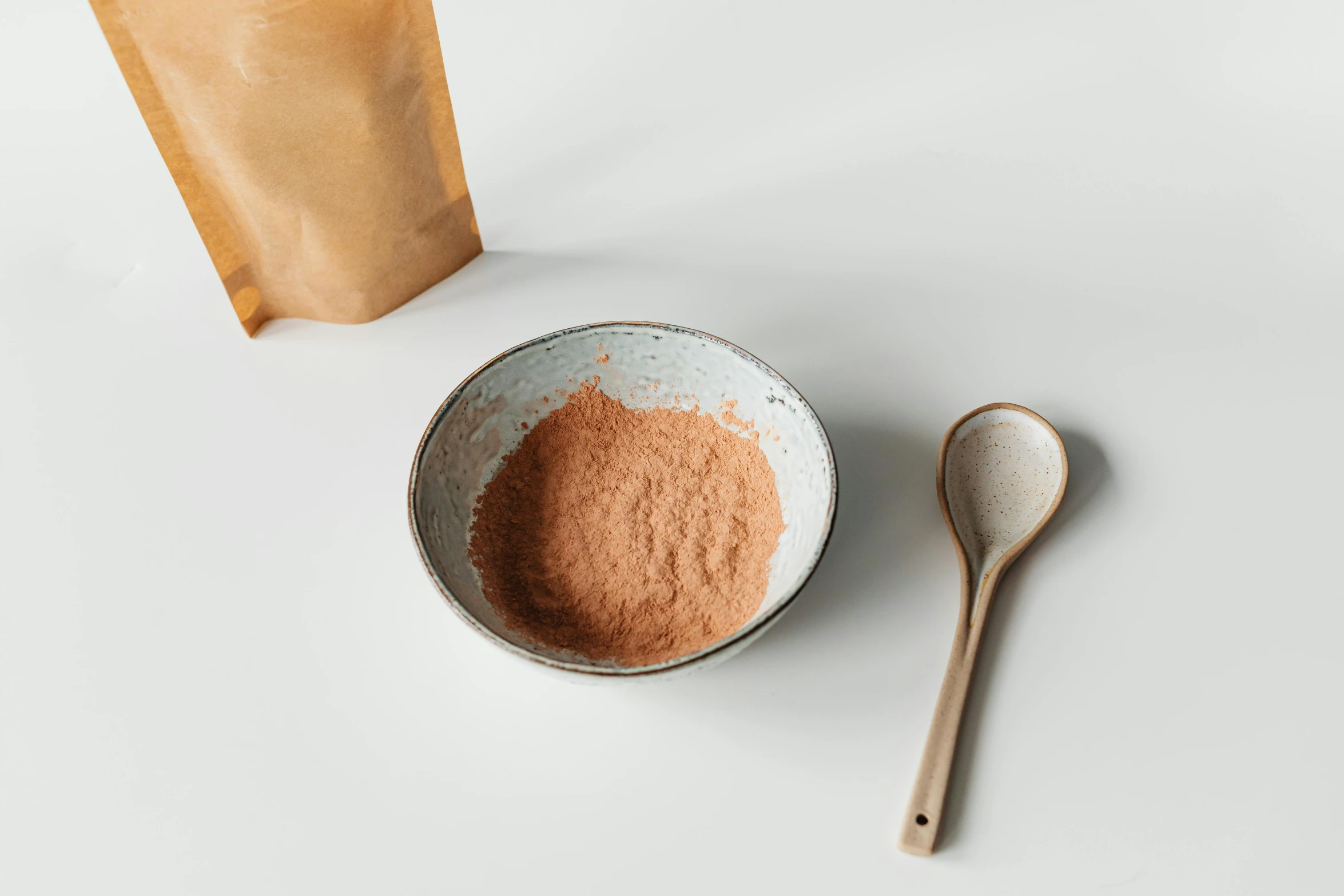 a white bowl filled with brown powder and a spoon